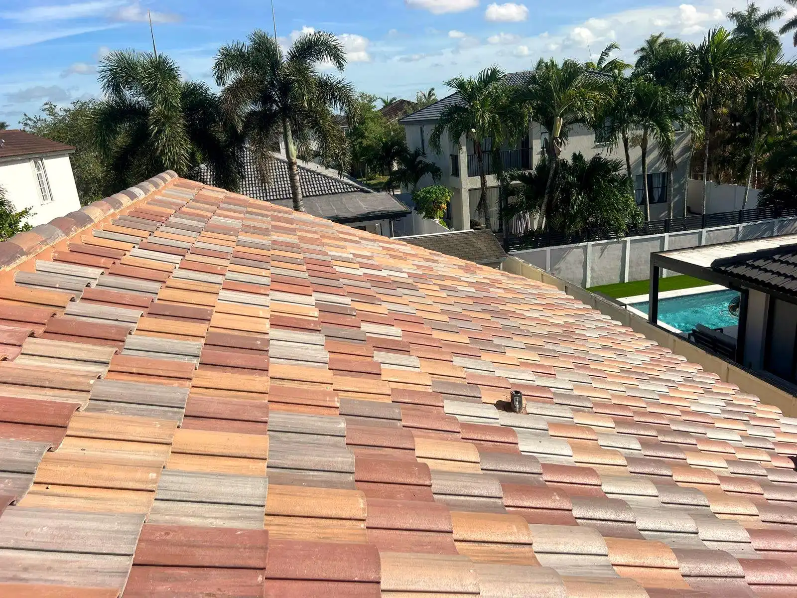 Blend-color tile roof seen from above, with palm trees beyond