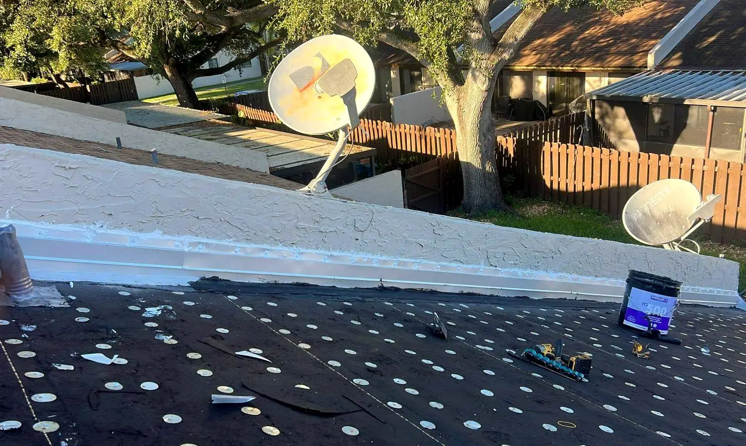 New metal flashing along a parapet wall and a pipe vent, over cap-nailed underlayment
